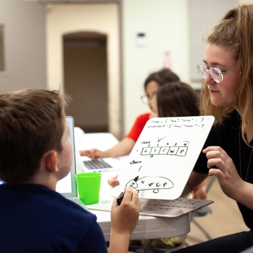 Instructor showing code logic on a white board to a student