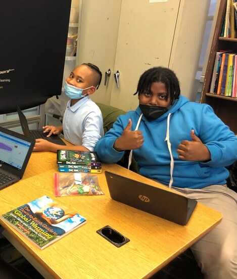 Two boys coding while wearing masks